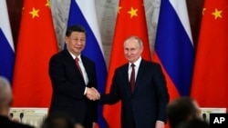 资料照:俄罗斯总统普京与中国领导人习近平在俄罗斯克里姆林宫举行会谈后在一个签字仪式上向媒体讲话后握手。(2023年3月21日)