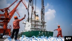 在中国江苏省张家港的一个港口,工人们正在卸载装着化学品的袋子。