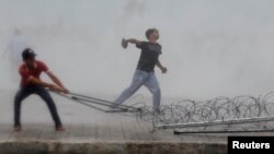 Người biểu tình ném gạch và tìm cách kéo đổ hàng rào kẽm gai trong khi xô xát với cảnh sát gần khu Hoàng cung trong thủ đô Phnom Penh, 15/9/13