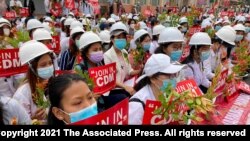 2021年2月21日在曼德勒举行的反政变游行中,医学院学生戴着口罩,举着标语牌聚集在一起。