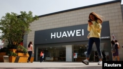 一名女子看着手机走过北京一家华为商店。(2019年5月16日)