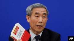 中国人大常委会副秘书长李飞在记者会上手持中国法律书(2016年11月7日)