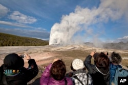 在黄石国家公园,游客给“老忠实”喷泉拍照(2011年5月21日)