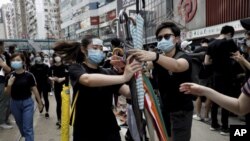 香港抗议者星期天(7月28日)在中环分发雨伞。美联社