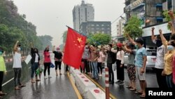 资料照片:反对军政府政变的抗议人士在示威活动中准备点燃一面中国国旗以表达不满。(2021年4月5日)