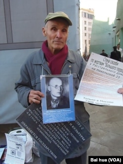 涅斯杰连科手持被处决的父亲照片,以及介绍当年最高军事法庭的资料,他呼吁把最高军事法庭遗址改建成红色恐怖博物馆 (美国之音白桦拍摄)