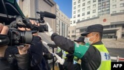 资料照片:一名警察挡住记者的镜头阻止拍摄审讯公民记者张展的上海浦东新区法院外景。(2021年12月28日)