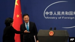 资料照片:中国外交部发言人华春莹引导新任发言人赵立坚走入例行记者会会场。(2020年2月24日)