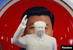 资料照片:北京天安门附近一个纪念品商店里毛泽东的塑像摆在习近平纪念画盘的前面。(2018年3月1日)