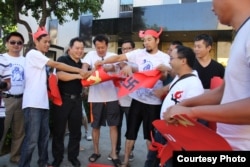 示威者撕毁中共党旗和纳粹标志的海报(成生提供)