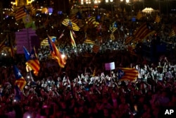 人们在西班牙巴塞罗那街头游行,手中挥舞着加泰罗尼亚旗帜