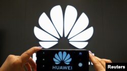 一支手机屏幕上显示的华为标识。(资料照:)