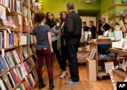 感恩节过后“小企业星期六”奥巴马总统带着两个女儿在厄普舍书店与经理安娜·索恩交谈。(2015年11月28日)