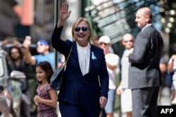 希拉里.克林顿在女儿的公寓里休息后,离开公寓楼,对记者们挥手致意(2016年9月11日)