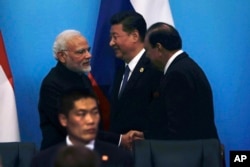 在中国东部山东省青岛举行的上海合作组织峰会上,印度总理莫迪同巴基斯坦总统侯赛因握手,中国国家主席习近平在旁边(2018年6月10日)。