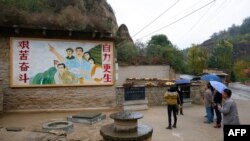 资料照片:在陕西省梁家河,中国最高领导人习近平青年时期生活过的窑洞外面,有一幅描绘青年习近平指引方向的壁画。(2016年10月22日)