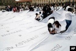 Demonstrators install white sheets covered with the names of victims of Colombia’s internal conflict in downtown Bogota, Colombia, October 11, 2016. The giant quilt is part of artist Doris Salcedo’s “Adding Absences” project.
