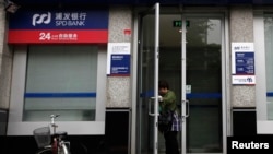 一名女士打开上海浦东发展银行开设在北京的一所支行的大门。(2011年7月6日)