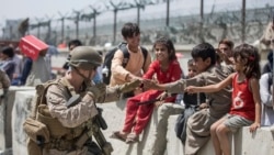 美国海军陆战队提供的图像显示,一名海军陆战队空地特遣队成员在喀布尔哈米德·卡尔扎伊国际机场与等待办理撤离手续的阿富汗儿童游戏。(2021年8月20日)