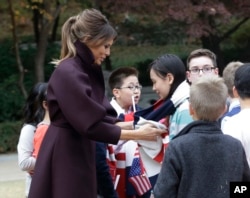 美国第一夫人梅拉尼亚在韩国总统府青瓦台给一个女孩儿戴上围巾(2017年11月7日)