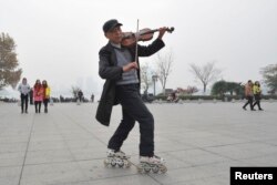 一位穿着旱冰鞋的男士在雾霾笼罩下的南京市的一座广场上拉着小提琴。(2013年12月5日)