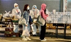 1月26日晚油麻地封锁区内需要接受突袭式强制检测的居民,领取政府派发的食物等物资。 (美国之音/汤惠芸)