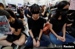 香港反送中示威者2019年8月12日在香港国际机场静坐示威时用黑布蒙眼,抗议警方一天前与示威者的冲突中使一名抗议者眼睛受伤。