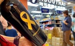 香港市民丁小姐在沙田一间阿布泰分店排队约40分钟,购买阿布泰独家发售,2019年酿制、贴上象征自由的黄丝带及香港加油标贴的红酒 (美国之音/汤惠芸)