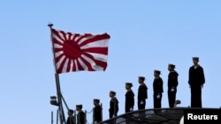 2015年3月25日,日本海军站在即将起航的出云级护卫舰甲板上,这艘军舰即将驶离东京南部的横滨日本联合海上造船厂。