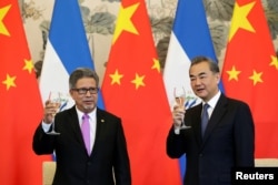 萨尔瓦多外长卡斯塔内达(左)和中国外长王毅在北钓鱼台国宾馆举行的建交仪式上举杯庆贺。(2018年8月21日)