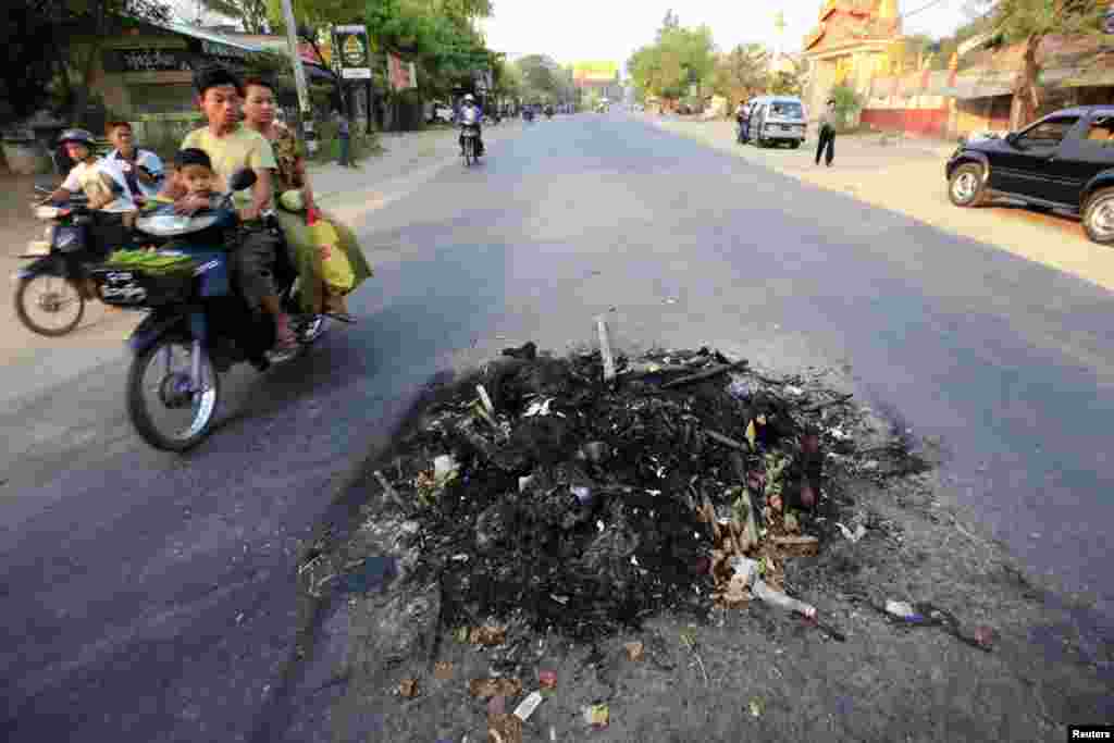 2013年3月22日,在密铁拉镇,人们骑着轻骑摩托经过两名死于冲突者的尸体。