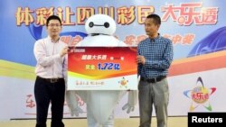 资料照:一名彩票中奖者在中国四川成都举行的领奖仪式上装扮成充气机器人大白领取1.72亿元人民币的彩票金。(2015年4月16日)