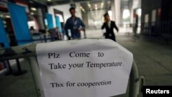 Tấm bảng tại lối ra vào Hội chợ Canton ở Quảng Châu, tỉnh Quảng Đông, Trung Quốc hôm 26 tháng 10, 2014 yêu cầu khách vào hội chợ đến đo thân nhiệt.