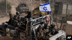 以色列士兵乘坐挂有以色列国旗的军车穿过叙利亚和被以色列控制的戈兰高地之间的阿尔法线附近的安全栏。(2024年12月12日)