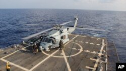 美国海军一架直升机在暹罗湾参加失踪马航班机搜救任务后在“平克尼号”导弹驱逐舰着陆换班。(2014年3月9日)