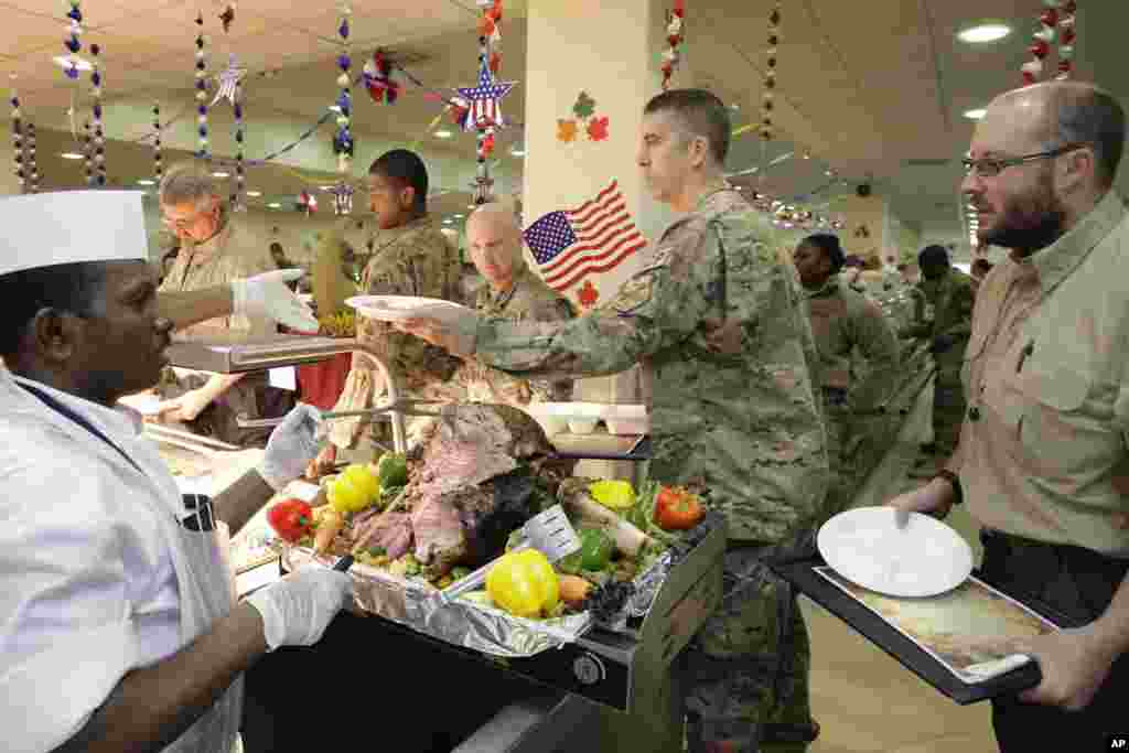 2012年11月22日,感恩节大餐开饭时间到了,一位餐厅员工(左)在以美国为主导的联军驻阿富汗喀布尔的基地为军人和文职人员服务。