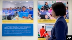 资料照:在乌鲁木齐举办的打击恐怖主义与极端主义的展览会上,一名解说员站在显示新疆维吾尔等少数民族在训练营里的生活照片前。(2021年4月21日)
