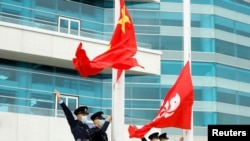 2021年3月11日,在中国香港金紫荆广场举行的升旗仪式上,警察在中国和香港的旗帜旁做手势。