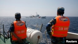 资料照:越南海岸警卫队成员在南中国海海域注视着一艘中国海警船只。
