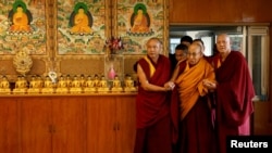 西藏精神领袖达赖喇嘛在印度达兰萨拉的住所内在僧侣的扶助下步入大厅。(2024年12月20日)