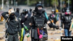 An anti-government protester holds a molotov cocktail alongside others on a road scattered with bricks outside the Polytechnic University in Hong Kong, Nov. 16, 2019.