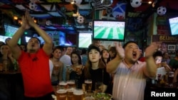 2018年6月14日,人们在北京的一家酒吧观看世界杯甲组俄罗斯对沙特阿拉伯足球比赛,他们看得很投入,聚精会神。