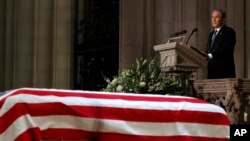 前总统小布什在覆盖着美国国旗的老布什灵柩前致悼词,深情缅怀父亲。(2018年12月5日)