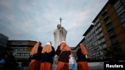 2025年3月8日,罗马杰梅利医院外,修女们聚集在临时纪念碑附近,教皇方济各正在那里接受双肺炎治疗。