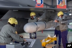 资料照:台湾嘉义一个空军基地的地勤人员在一架F-16战机的机翼上安装导弹。(2023年1月6日)