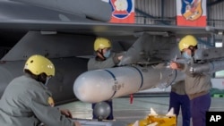 资料照:台湾嘉义一个空军基地的地勤人员在一架F-16战机的机翼上安装导弹。(2023年1月6日)