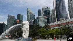 资料照片: 2020年6月30日,人们在新加坡滨海湾地区拍摄鱼尾狮雕像。