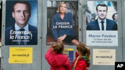 2017年5月5日,法国总统决选前,西南部奥赛的儿童走过马克龙和勒庞的总统大选海报。