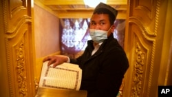 资料照:在政府组织的外国记者访问中国新疆一名维吾尔族男子阿克苏的家中时,他拿着一本阿拉伯语和维吾尔语的《古兰经》。(2021年4月20日)