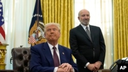 资料照片:特朗普总统在白宫椭圆形办公室回答记者提问时,被提名为商务部长的卢特尼克站在旁边。(2025年2月13日)